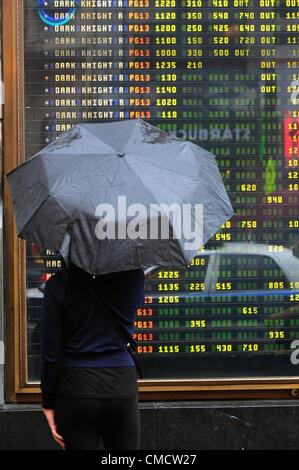 20. Juli 2012 - Manhattan, New York, USA - Menschen betrachten über Spielzeiten der AMC 25 Theater am Times Square nach Batman "Dark Knight Rises" Theater Dreharbeiten in Aurora, Colorado. Mindestens 12 Menschen wurden getötet und mehr als 50 verletzt während der Mitternacht-Premiere des Films an den Jahrhundert 16 Kinos in Aurora. (Bild Kredit: Bryan Smith/ZUMAPRESS.com ©) Stockfoto