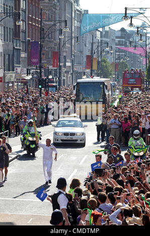 London, UK. 26. Juli 2012. Die Olympische Fackel erfolgt durch Rene Fasel - IOC-Mitglied und Präsident der International Ice Hockey Federation, durch Londons Modehauptstadt Oxford Circus. 26. Juli 2012 Stockfoto