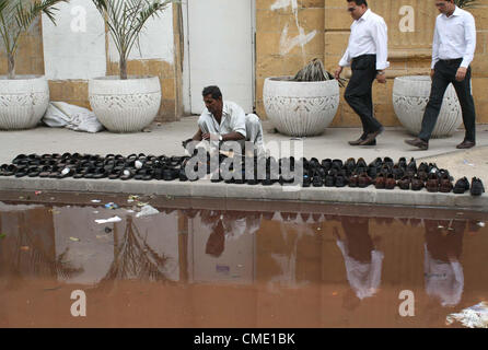 Ein Mann verkauft verwendet Schuhe, seinen Lebensunterhalt für die Unterstützung seiner Familie wartet auf Kunden in der Nähe Stand Kanalisation Wasser bei Tower Road zeigt die Fahrlässigkeit der betreffenden Abteilung in Karachi auf Freitag, 27. Juli 2012 zu verdienen. Stockfoto