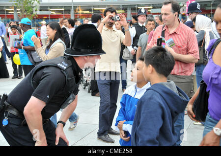 Stratford, London, UK. 27. Juli 2012. Ein freundlicher Polizist spricht mit Kindern wie jeder Party-Atmosphäre außerhalb der Westfield Centre genießt, wie Menschen am Bahnhof Stratford entfernt für die Eröffnungsfeier der Olympischen Spiele die London2012 ankommen. Einige Tickets, einige ohne, aber alles voller Spannung, wie die Spiele endlich beginnen. Stockfoto