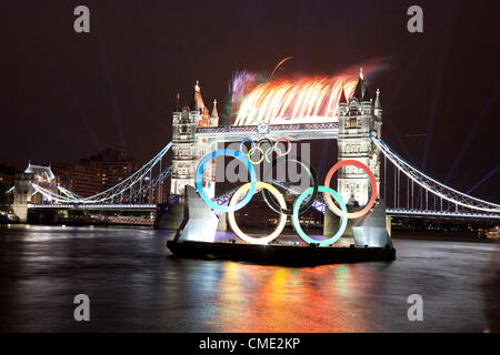 London, UK. Freitag, 27. Juli 2012. Olympische Flamme geht Tower Bridge mit Feuerwerk auf Weg zur Eröffnungsfeier. Londons größte Wahrzeichen Brücke leuchtet, während die Olympische Fackel in einem high-Speed-Boot vorbei. Stockfoto