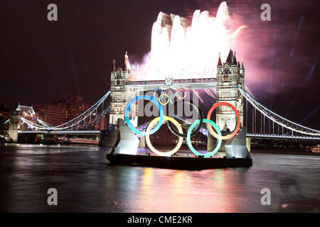 London, UK. Freitag, 27. Juli 2012. Olympische Flamme geht Tower Bridge mit Feuerwerk auf Weg zur Eröffnungsfeier. Londons größte Wahrzeichen Brücke leuchtet, während die Olympische Fackel in einem high-Speed-Boot vorbei. Stockfoto