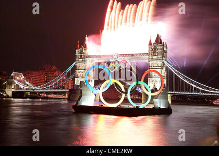 London, UK. Freitag, 27. Juli 2012. Olympische Flamme geht Tower Bridge mit Feuerwerk auf Weg zur Eröffnungsfeier. Londons größte Wahrzeichen Brücke leuchtet, während die Olympische Fackel in einem high-Speed-Boot vorbei. Stockfoto