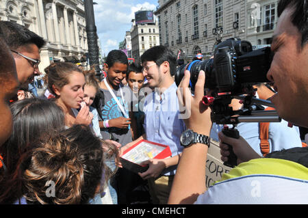 Piccadilly Circus, London, UK. 30. Juli 2012. Ein Fernsehteam von Koreanisch verschenken kostenlose koreanische Plätzchen. Die Olympischen Spiele 2012 in London lockt Fernsehteams aus aller Welt um die Spiele zu decken und den Geist und die Atmosphäre der Stadt zu erfassen, wie es die Spiele veranstaltet. Stockfoto