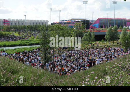 Zuschauer im Park leben Osten im 2012 Olympic Park beobachten die großen TV-Berichterstattung von den Olympischen Spielen mit der Hockey-Ufer-Arena im Hintergrund, auf Freitag, 3. August 2012. Stockfoto