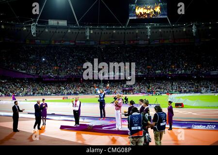 4. August 2012 - London, England, Vereinigtes Königreich - mit the Olympic Cauldron drohend über dem Stadion, springt britische Hepthathalon Athlet JESSICA ENNIS (C) auf dem Podium, ihre Goldmedaille sowie Silbermedaillengewinner JESSICA ZELINKA und Bronzemedaillengewinner BRIANNE THEISEN während der 2012 London Sommer-Olympiade zu erhalten. (Kredit-Bild: © Mark Makela/ZUMAPRESS.com) Stockfoto