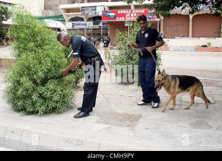 10. August 2012. Sicherheitsbeamter prüft mit Hilfe von Snuffer-Hund auf der Strecke der Prozession der schiitischen Trauergemeinde M.A Jinnah Road als Sicherheit während der Todestag von Hazrat Imam Ali bin Abu Talib (AS) in Karachi auf Freitag, 10. August 2012 verschärft hat. Stockfoto