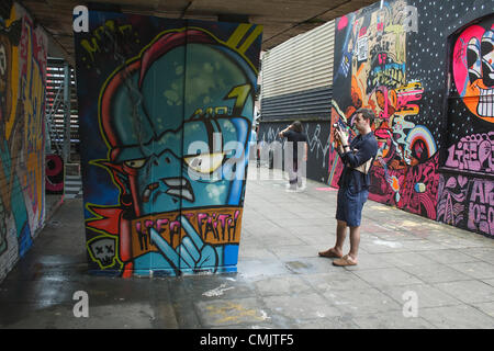 Bristol, Großbritannien. August 2012. Ein Mann fotografiert ein Kunstwerk, das auf Gebäuden in der Nelson Street für das Street Art Festival See No Evil gemalt wurde. See No Evil ist eine Sammlung von öffentlichen Kunstwerken, die von mehreren Graffiti- und Urban-Street-Künstlern in und um die Nelson Street in Bristol, Großbritannien, geschaffen wurden. Stockfoto