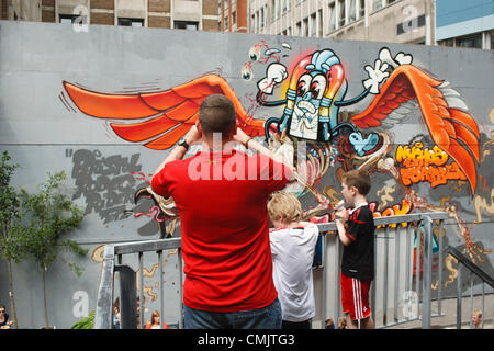 Bristol, Großbritannien. August 2012. Ein Mann fotografiert ein Kunstwerk, das auf Gebäuden in der Nelson Street für das Street Art Festival See No Evil gemalt wurde. See No Evil ist eine Sammlung von öffentlichen Kunstwerken, die von mehreren Graffiti- und Urban-Street-Künstlern in und um die Nelson Street in Bristol, Großbritannien, geschaffen wurden. Stockfoto