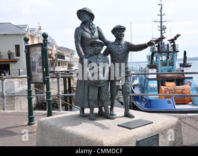 Eine Skulptur von Jeanne Rynhart am Kai vor dem Cobh Heritage Centre zeigt dem Weggang von Annie Moore, ein junges Mädchen im Alter von 15 und ihre zwei jüngeren Brüder, die Queenstown (Cobh heute benannt) für New York, Foto 25. Mai 2013 verlassen. Am 1. Januar 1892 war Annie der erste Einwanderer im neu eröffneten Zentrum Ellis Island in New York verarbeitet werden. Die Skulptur steht als Symbol für die viele Iren, die Irland wegen Armut, Missernten, Hunger und Krankheit zu verlassen. Cobh war der Ausgangspunkt für etwa 2,5 Millionen Iren ausgewandert nach Nordamerika zwischen 1848 und Stockfoto