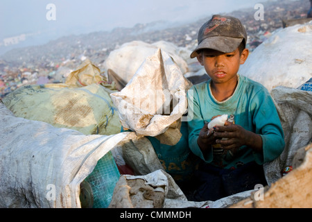 Ein junges Kind Arbeiter junge sucht durch Müll für Plastik an der Stung Meanchey Deponie in Phnom Penh, Kambodscha. Stockfoto