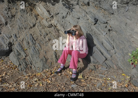 Ein 9 Jahre altes Mädchen auf der Suche nach Vögel durch ein Fernglas Stockfoto