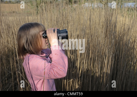 Ein 9 Jahre altes Mädchen auf der Suche nach Vögel durch ein Fernglas Stockfoto