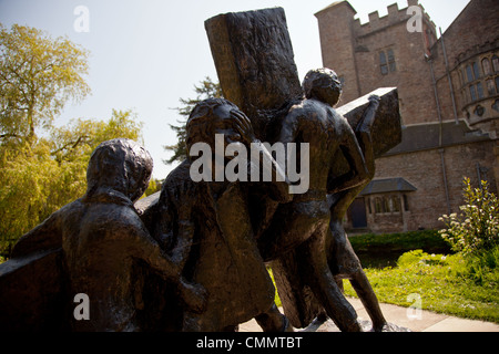 Bronze Statue, die vier Personen tragen ein Kreuz, religiöse symbolische Statue in Bischöfe Palastgärten, Wells, Somerset, Großbritannien. Stockfoto