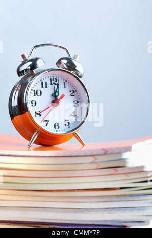 Stapel von Heften mit Wecker auf seiner Spitze Stockfoto
