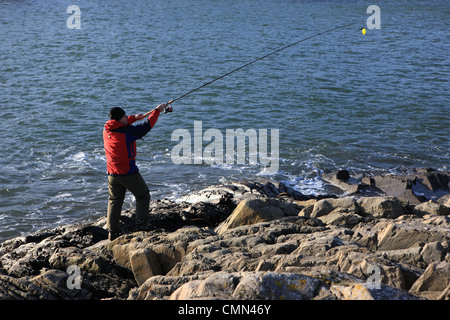 Man wirft eine Angelrute am Rand Wassers Stockfoto