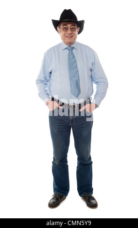 Foto Portrait of senior Männchen tragen einen Cowboyhut und posiert mit Hände in Tasche Stockfoto