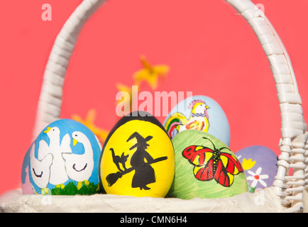 Bunte Ostereier in einem Korb vor hellen rosa Hintergrund Stockfoto