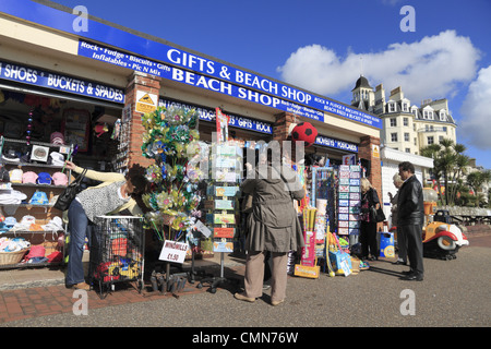 Touristen, die die Postkarten und Geschenke an einem Strand surfen vorne Shop auf Eastbourne Strandpromenade, East Sussex, England. Stockfoto