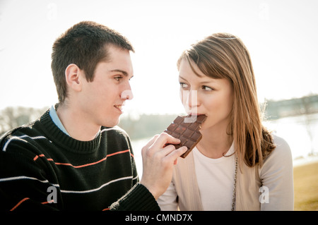 Junge Brautpaar zusammen outdoor - Mann Chcolate Frau gibt Stockfoto