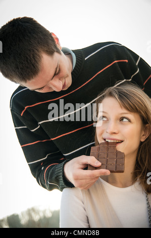 Junge Brautpaar zusammen outdoor - Mann Chcolate Frau gibt Stockfoto