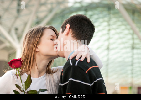 Junger Mann, Übergabe eine Blume (rote Rose) an Frau und küsste sie Stockfoto