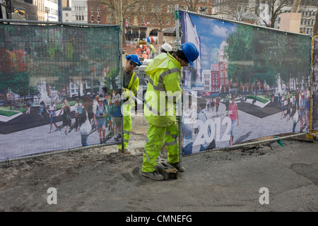 London-Auftragnehmer-Arbeiter schließen Bau Website Bildschirme, zeigt eine neue Entwicklung am Leicester Square für 2012. Stockfoto