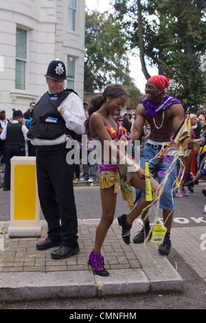 Ein Polizist schaut auf eine Tänzerin auf dem Notting Hill Carnival in London. Stockfoto