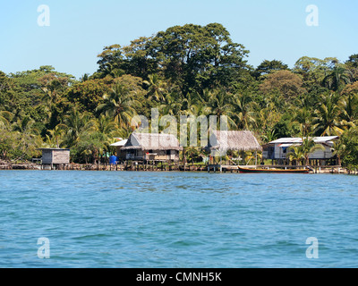 Rustikales haus mit strohgedeckten Hütte über Wasser und üppige tropische Vegetation an der karibischen Küste, Bocas del Toro, Panama, Mittelamerika Stockfoto