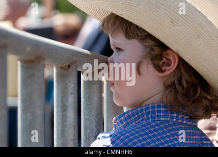 Kleiner Junge mit Cowboy-Hut mit Nase gegen Metallzaun gedrückt Stockfoto