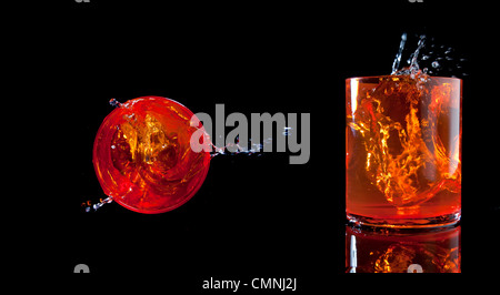 Orange farbigen Tumbler Glas mit Wasser spritzt Stockfoto