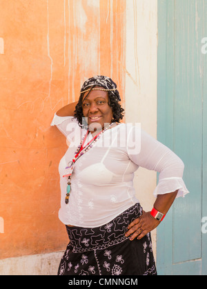 Ein Weibchen lizenziert Straßenhändler verkaufen Blumen in Havanna, Kuba lehnt sich gegen eine Wand von ihrem Blumenwagen. Stockfoto