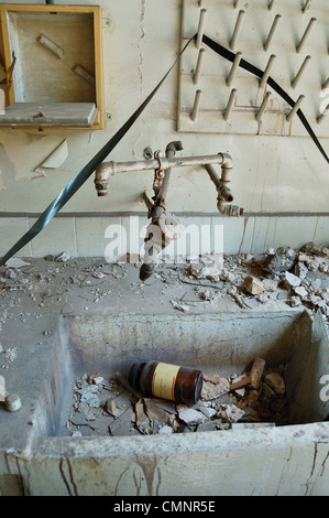 Schmutzigen industriellen Waschbecken mit zerbrochenem Glasflasche chemische Substanz und staubigen audio Reel Tape in verlassenen Fabrik. Stockfoto