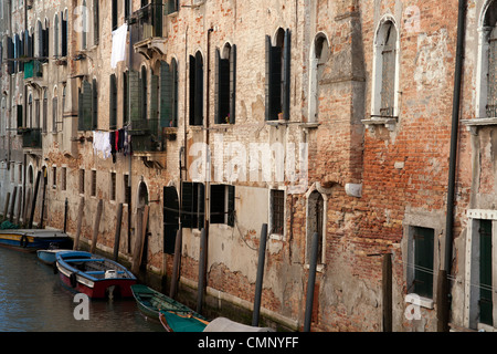 Ruderboote, festgemacht an einem Kanal übersehen von Fensterläden Venedig, Italien Stockfoto