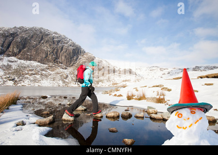 Frau Hill Wanderer durch eine gefrorene scheut Tarn in die saisonabhängige, Lake District, Großbritannien Stockfoto