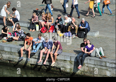 Touristen und Studenten genießen die erste Frühlingssonne am Wasser entlang der Graslei in Gent, Belgien Stockfoto