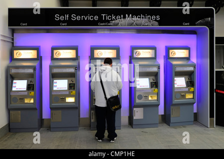 Person kauf Fahrkarte am Kings Cross Bahnhof Reihe von fünf self service Automaten akzeptieren Zahlung mit Kreditkarte oder Bargeld Camden London UK Stockfoto