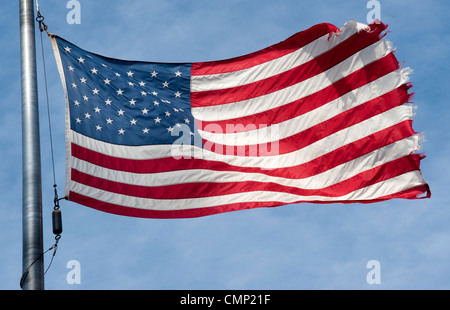 Zerfetzte amerikanische Flagge flattern im Wind auf einem blauen Himmel mit Wolken Stockfoto