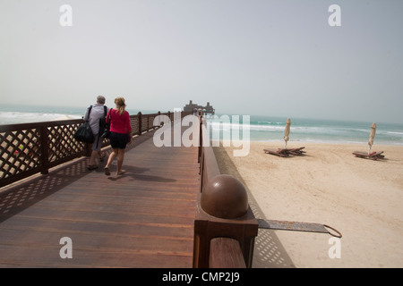 Ein Paar geht über eine Brücke, die vom Strand zum Pierchic Restaurant in Madinat Jumeirah führt und einen atemberaubenden Blick auf den Arabischen Golf, Dubai und die Vereinigten Arabischen Emirate bietet Stockfoto
