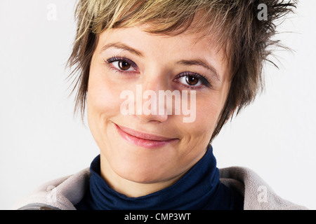 Attraktive junge Frau macht ein freundliches Gesicht - weiblichen Ausdruck mit einem hübschen Lächeln. Studio erschossen vor einem weißen Hintergrund. Stockfoto