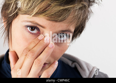 Schmerzhafte aussehende junge Frau hielt ihre Hand auf ihr Gesicht, Frauenporträt mit offenen Augen. Studio erschossen vor einem weißen Hintergrund Stockfoto