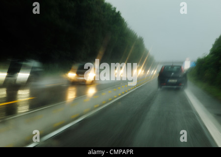 Vorsätzliche Bewegungsunschärfe. Fahren auf deutschen Autobahnen Autobahn in Nordrhein-Westfalen in der Nähe von Düsseldorf und Essen auf nassen Regentag Stockfoto