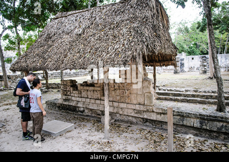 Chichen Itza Archäologische Zone Palast der Skulpturensäulen geschnitzte Steine Mexiko // Touristen schauen sich einige der geschnitzten Steine an, die Überreste des Palastes der Skulpturensäulen in der Chichen Itza archäologischen Zone in Mexiko sind. Stockfoto
