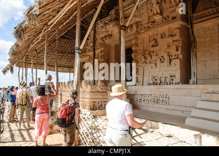 EK BALAM, Mexiko - Touristen bewundern die geschnitzten Verzierungen auf der Außenseite des Grabes von Ukit Kan Le'k Tok' auf der Akropolis auf der nördlichen Seite der Ek' Balam archäologische Stätte auf der mexikanischen Halbinsel Yukatan. Es war einst eine blühende Stadt der Maya Zivilisation dating bis Ende der Klassischen Periode. Es ist 30 km nördlich von Valladolid und ist für "Black Jaguar" ein charakteristisches Motiv der gesamten Website genannt. Stockfoto