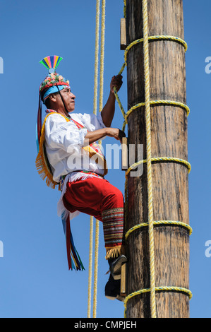 PLAYA DEL CARMEN, MEXIKO — einer der Darsteller klettert auf die Spitze einer hohen Stange, um eine traditionelle Maya-Zeremonie nachzubilden, bei der er von einer hohen Stange schwingen kann, die nur an Seilen befestigt ist, im Xcarat Maya-Themenpark südlich von Cancun und Playa del Carmen auf der mexikanischen Halbinsel Yucatana. Stockfoto