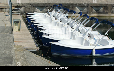 Linie von weißen und blauen Tretboote verankert am Hafen am See Stockfoto