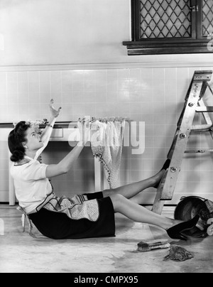 1940ER JAHREN FRAU HAUSFRAU VOM SCHRITT FALLEN LEITER IN KÜCHE BEIM WASCHEN FENSTER Stockfoto