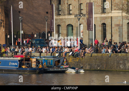 Menschen genießen die Sonne auf das Harbourside außerhalb Arnolfini Galerie in Bristol. Das Zentrum ist ein kultureller Hotspot der Stadt. Stockfoto