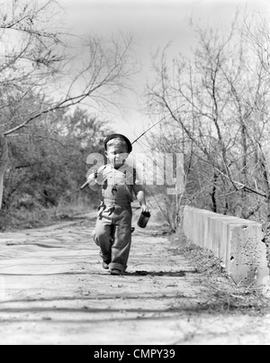 1940ER JAHRE JUNGEN HINUNTER LANDSTRAßE MIT BÜCHSE DER PANDORA UND ANGELRUTE Stockfoto