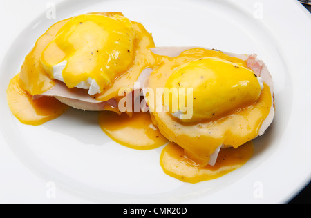 Eggs Benedict ist ein Gericht aus zwei Hälften von einem englischen Muffin, belegt mit Schinken oder Speck, pochierten Eiern und Sauce Hollandaise Stockfoto